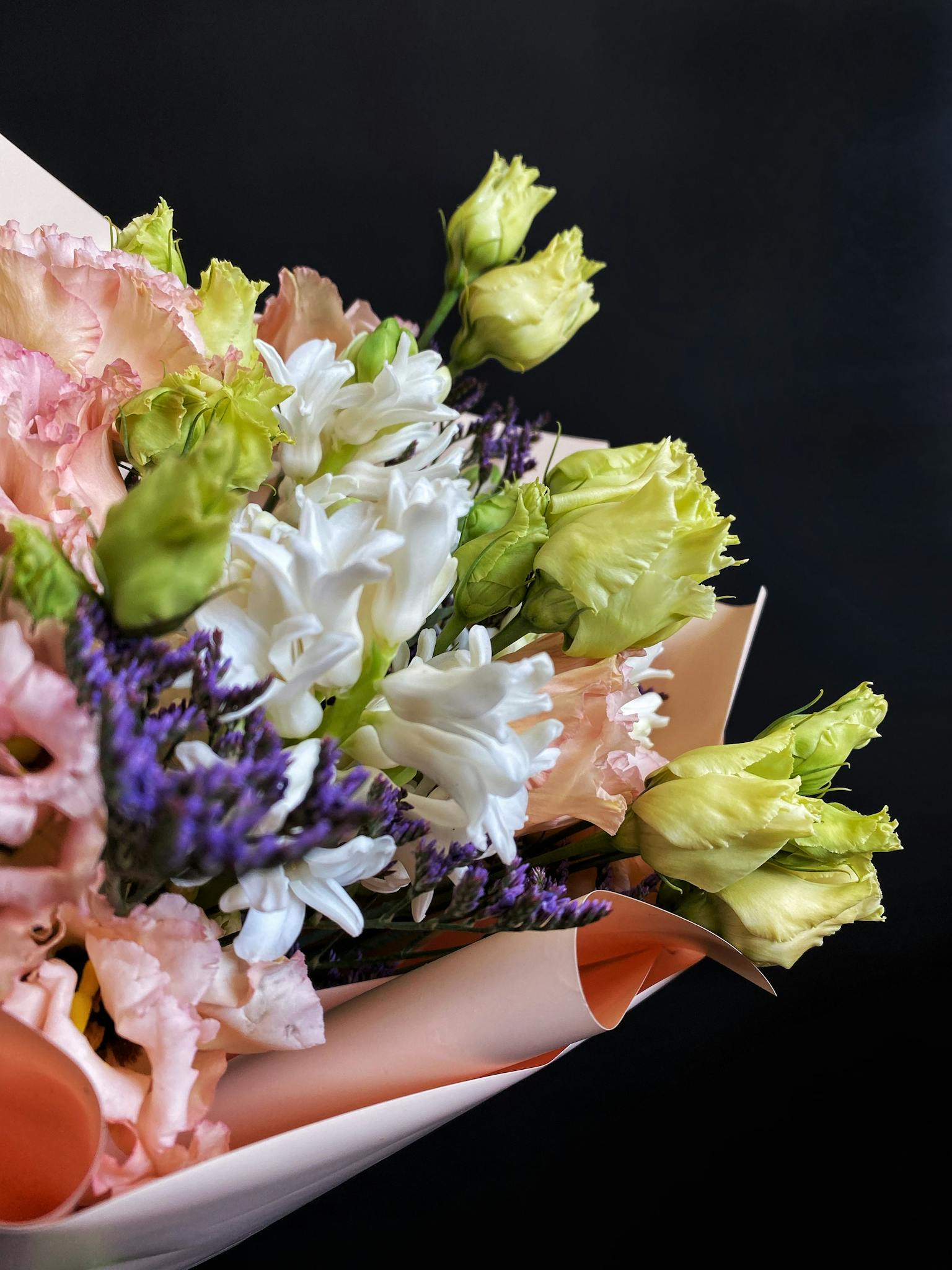 A vivid close-up of a mixed flower bouquet against a dark background.