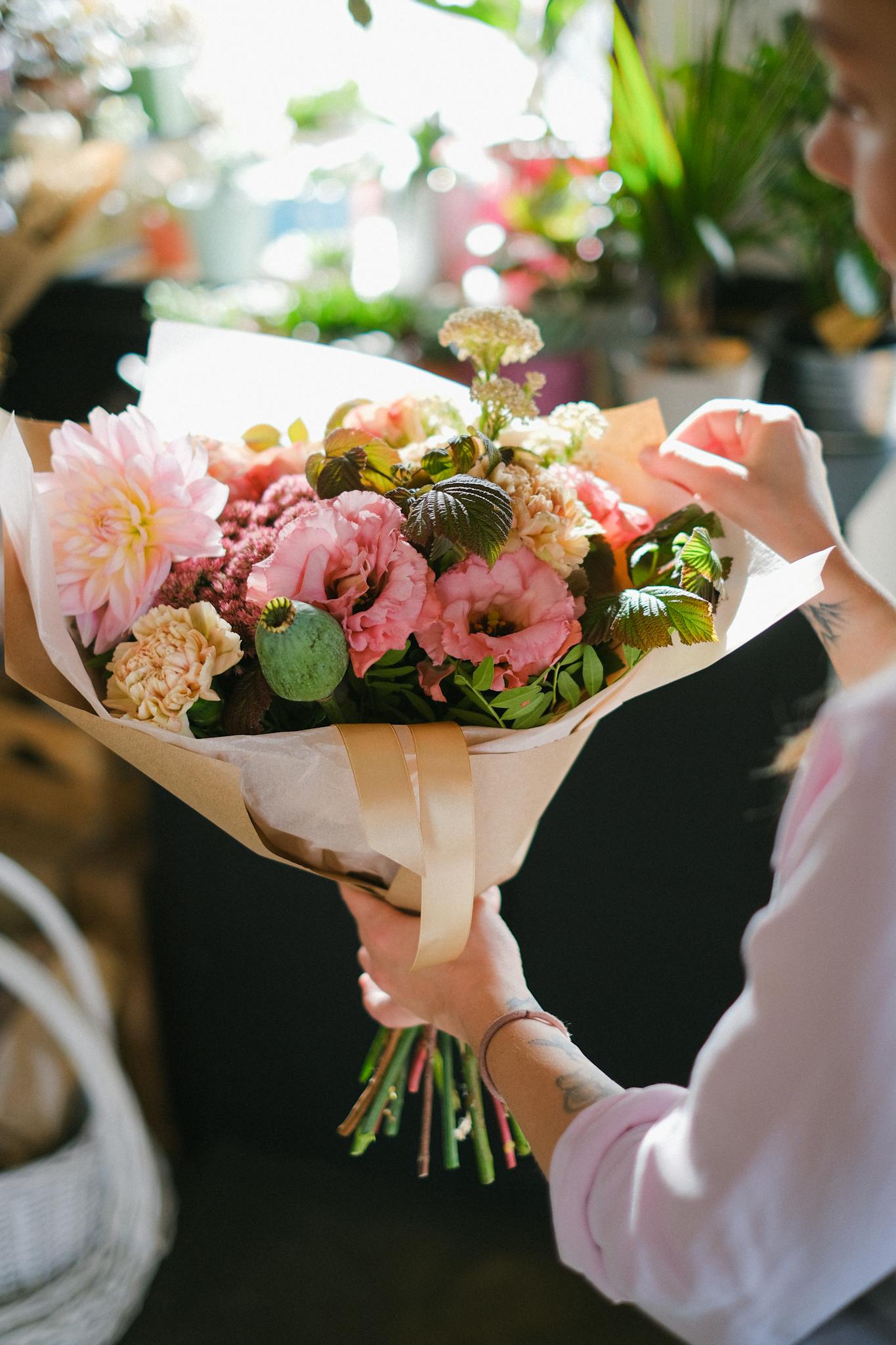 A woman gently holds a vibrant bouquet of mixed flowers indoors, creating a warm and intimate atmosphere.