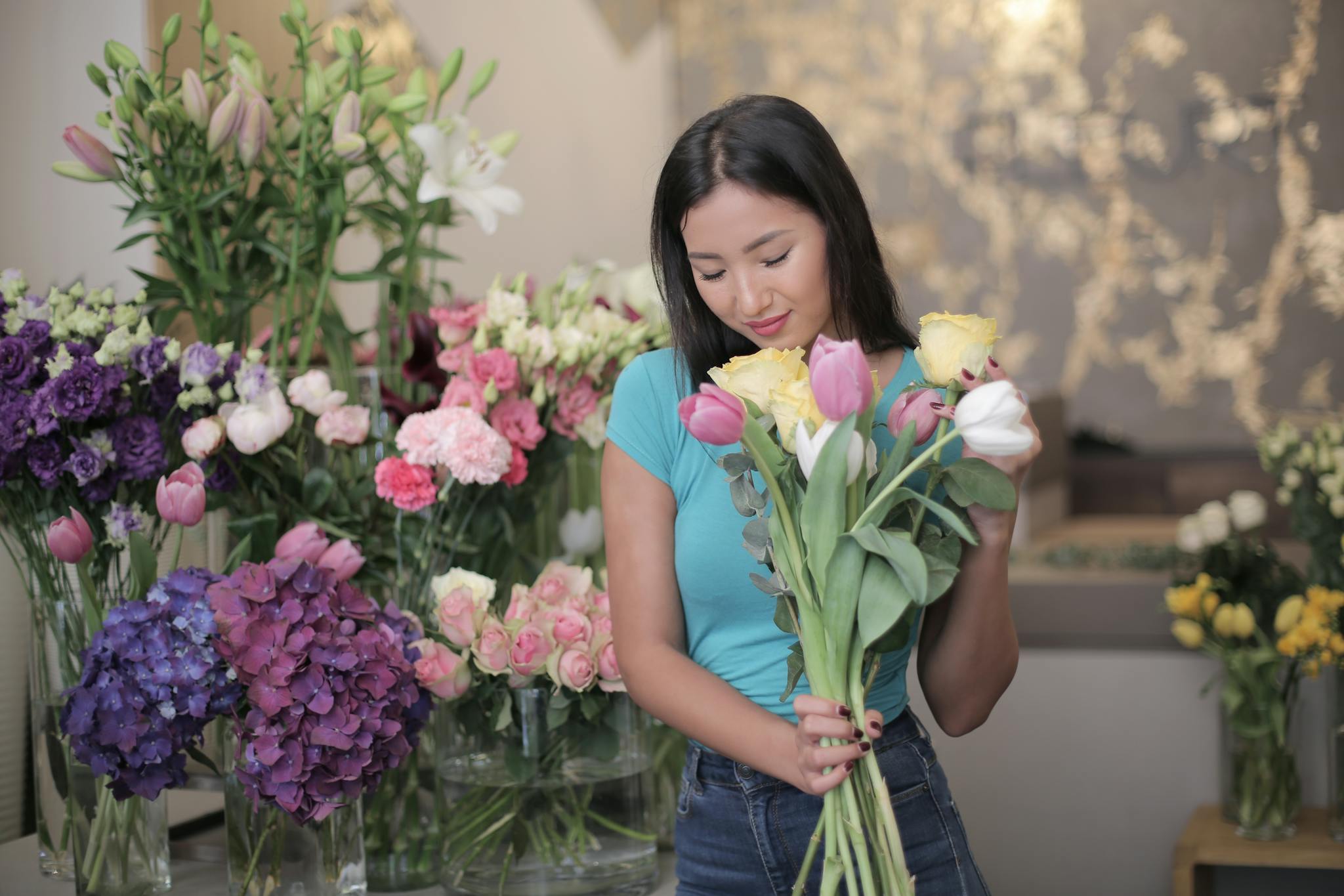 A woman joyfully holding a bouquet of fresh flowers inside a vibrant florist shop.