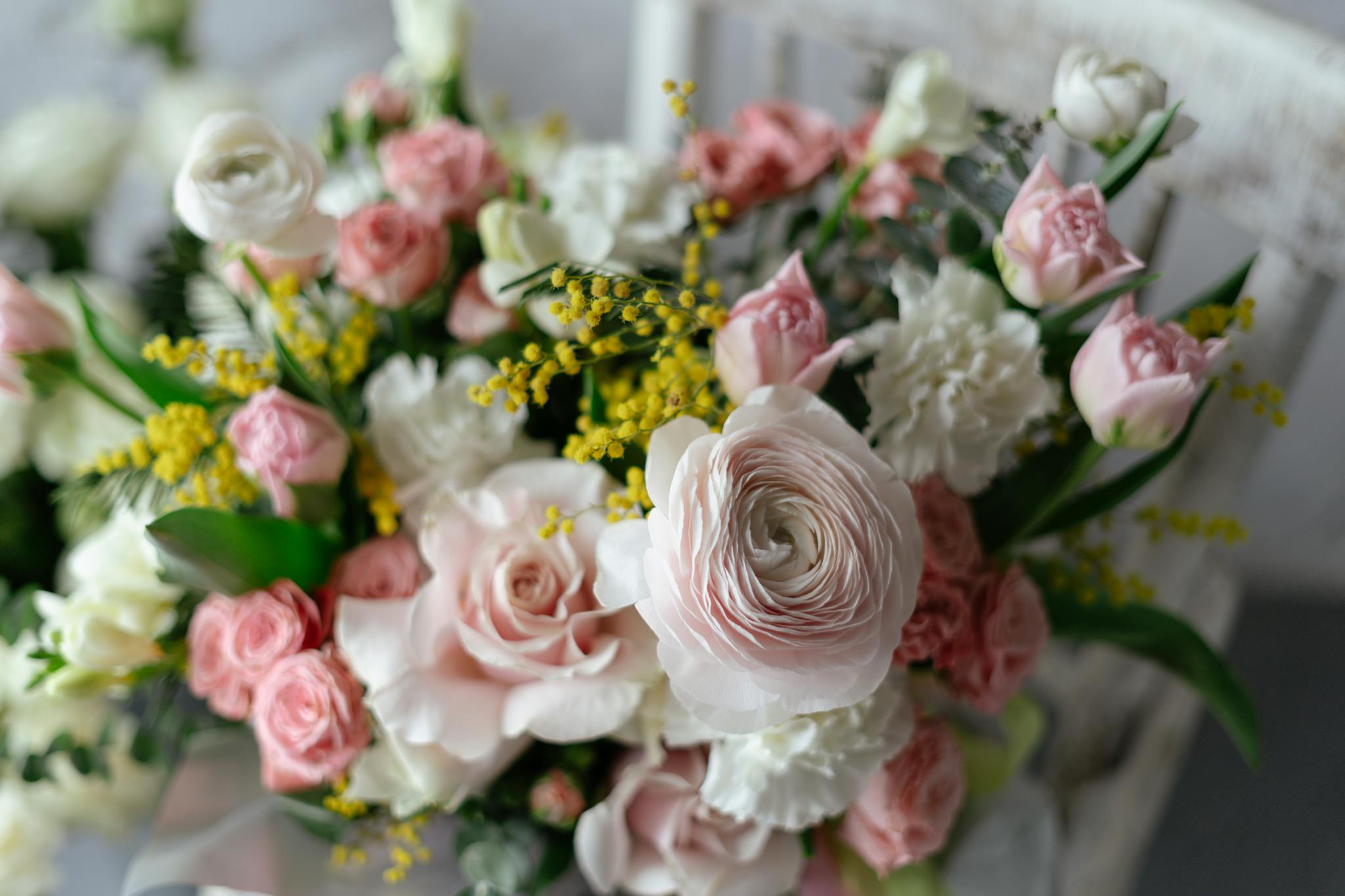 Delicate floral arrangement featuring roses and ranunculus in soft pink and white hues, perfect for springtime.